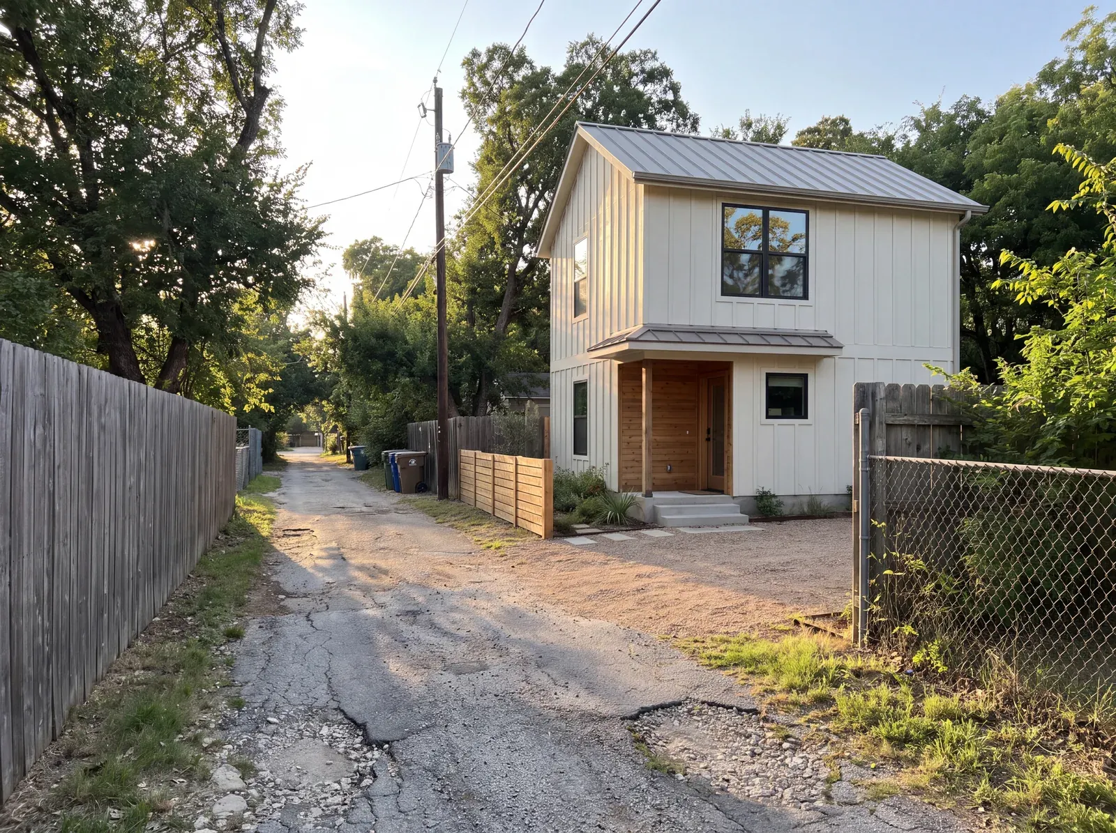 Two-story board-and-batten ADU with a standing-seam metal roof and cedar entry porch on an alley