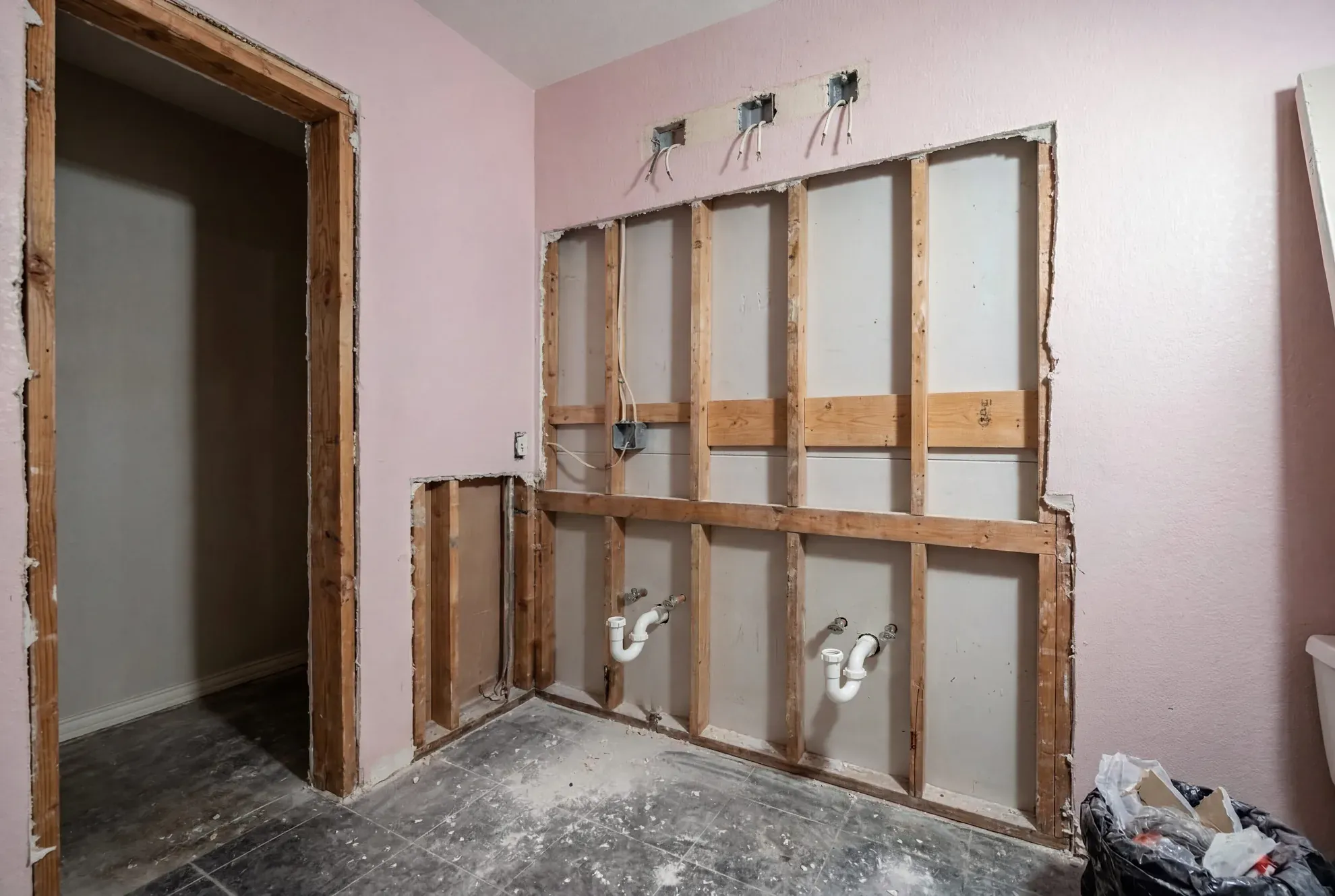 Open bathroom wall during rough-in with new plumbing supply lines and P-traps