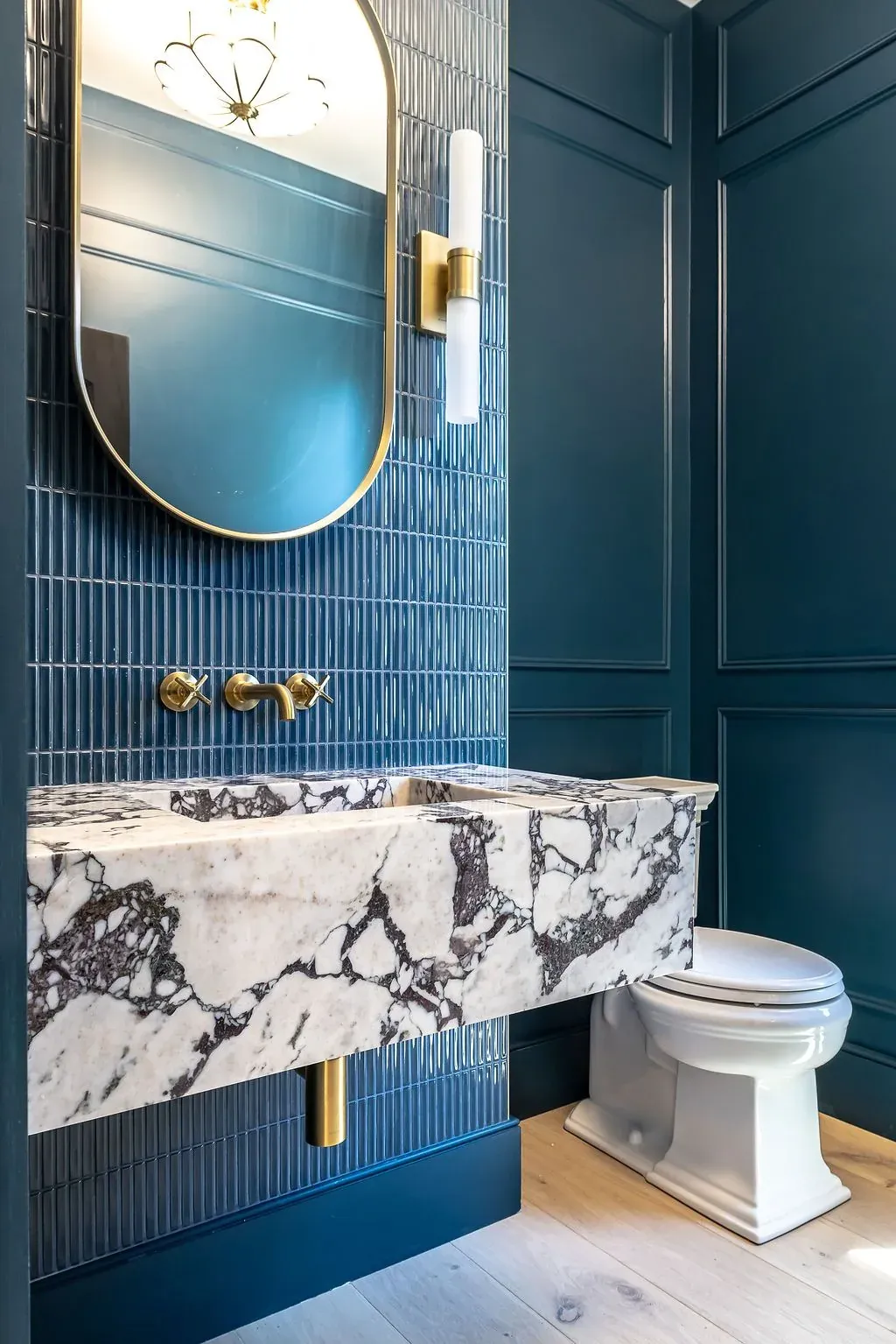 Powder room remodel in Austin, TX with fluted blue tile and a veined marble sink