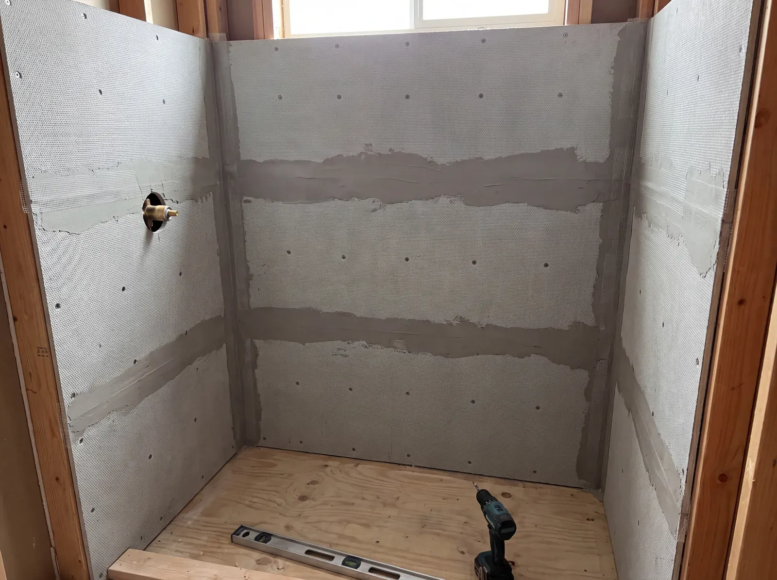 Cement board substrate installed in a shower surround with taped seams, before membrane application