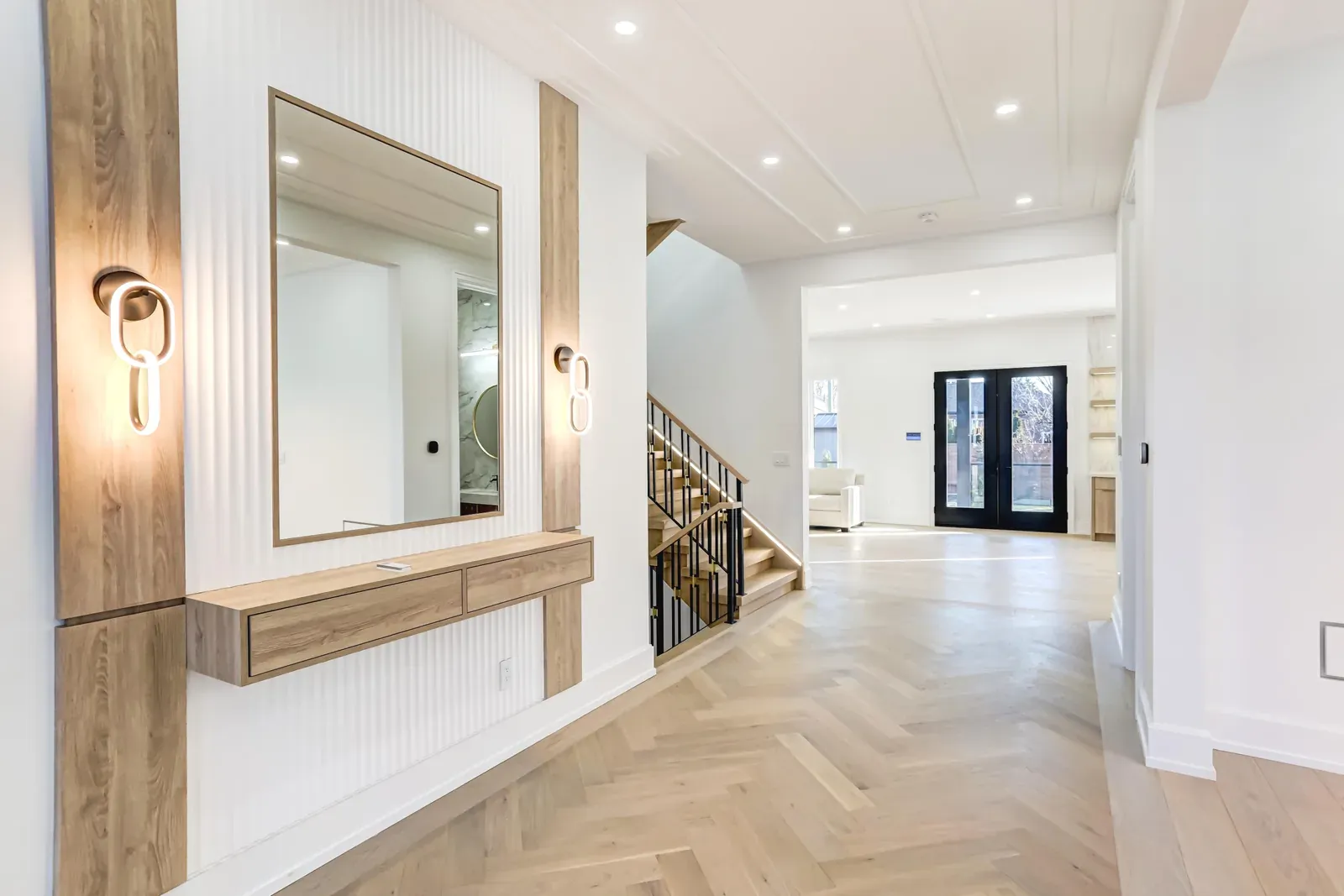 Entry hall with herringbone wood floors opening to a stair and living space