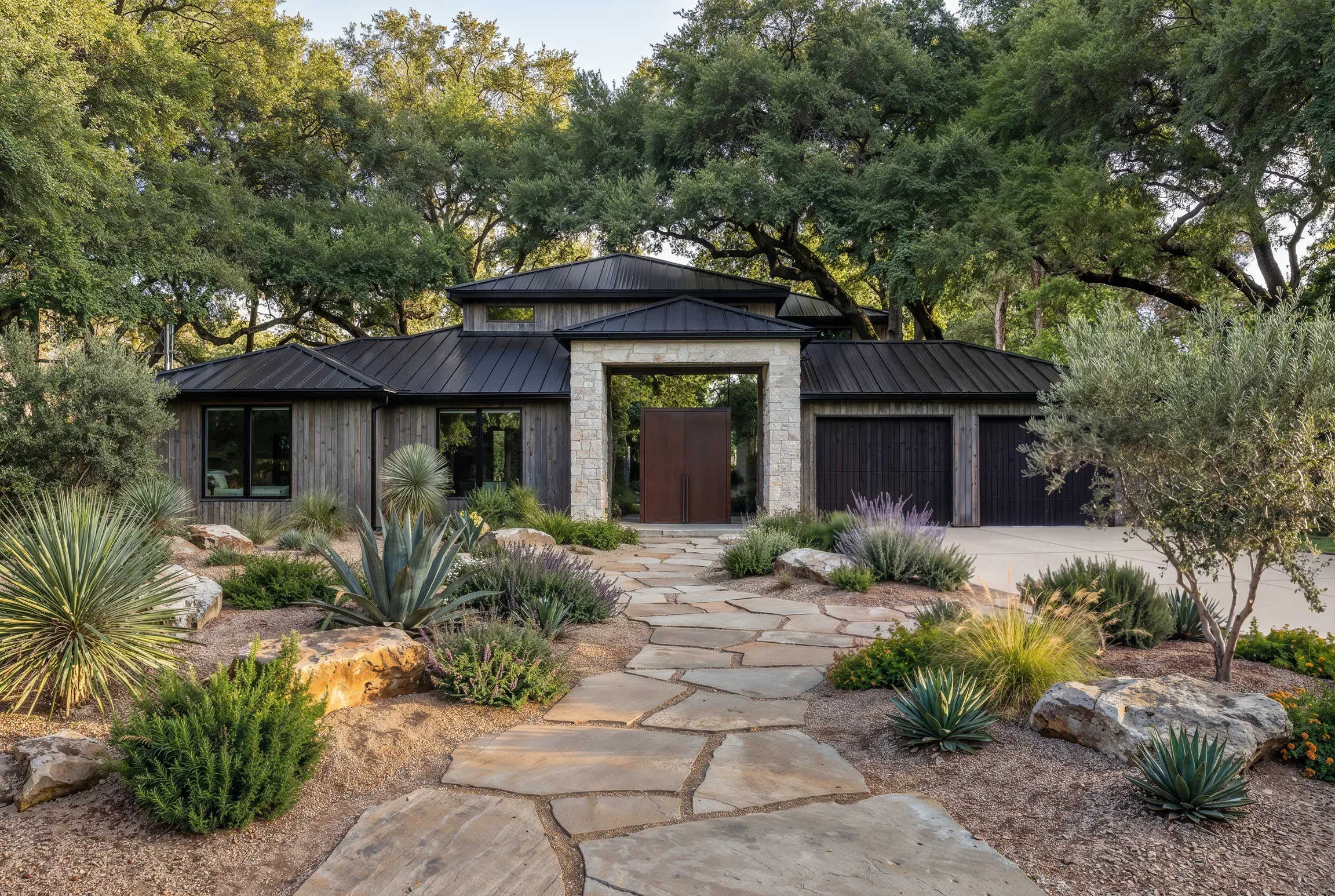 The same front yard eleven months later: a flagstone path, limestone boulders, and established native planting across the front of the house