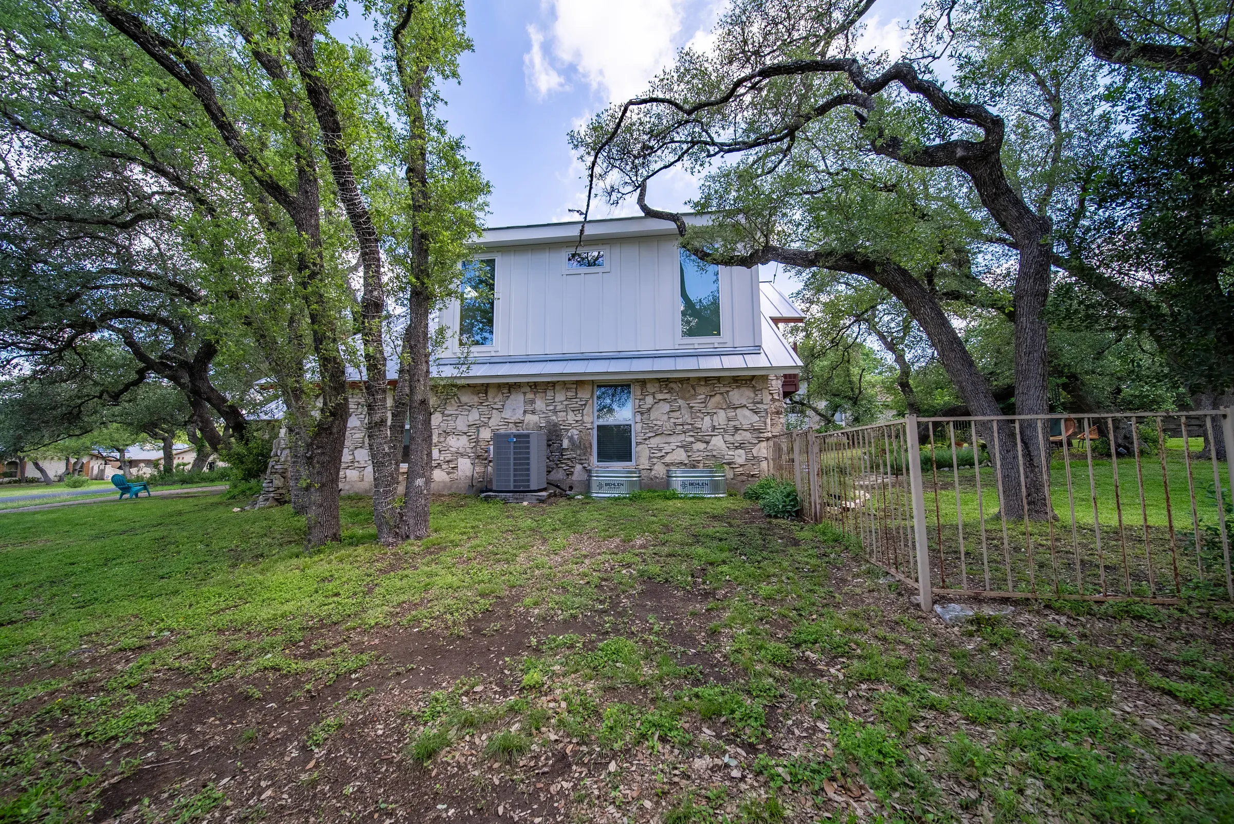 The same house after the addition: a white board-and-batten dormer storey built over the original stone walls