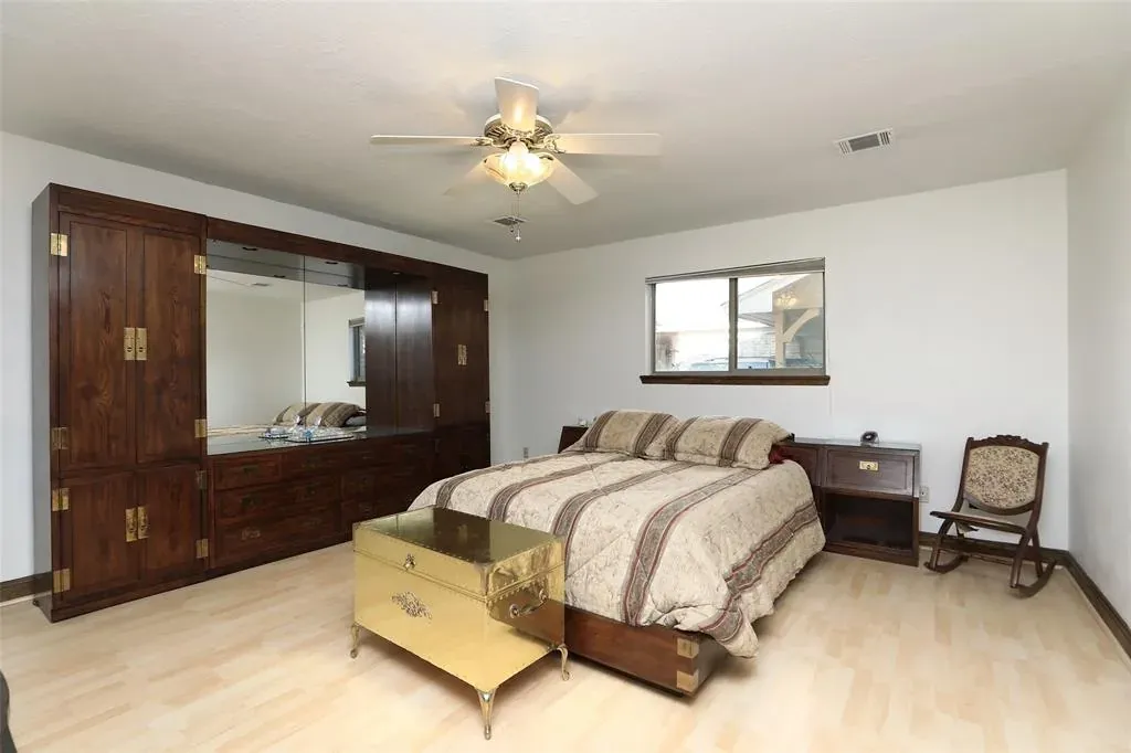Before: Whole home remodel in Mueller, Austin, TX with a dark wood armoire and a ceiling fan